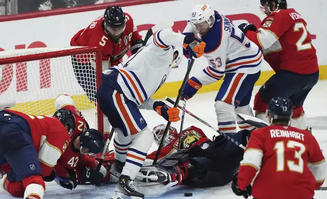 Florida Panthers goalie Sergei Bobrovsky, center bottom, makes a save as Edmonton Oilers' Trent Frederic, center, and Jeff Skinner (53) look for the puck during the first overtime period in Game 4 of the NHL hockey Stanley Cup Final in Sunrise, Fla., Thursday, June 12, 2025. (Nathan Denette/The Canadian Press via AP)