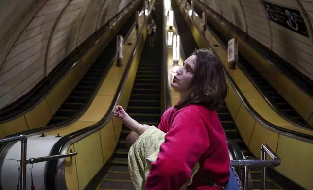 A woman calms her son as she takes cover at a metro station during a Russian drone strike on Kyiv, Ukraine, Tuesday, June 10, 2025. (AP Photo/Evgeniy Maloletka)