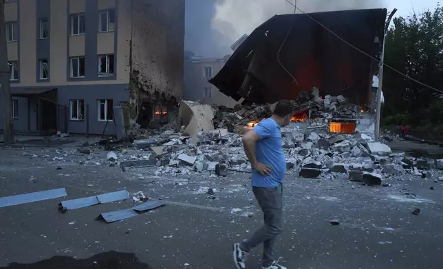 A resident reacts as he passes by burning debris following Russia's missile and drone attack in Kyiv, Ukraine, Tuesday, June 10, 2025. (AP Photo/Efrem Lukatsky)