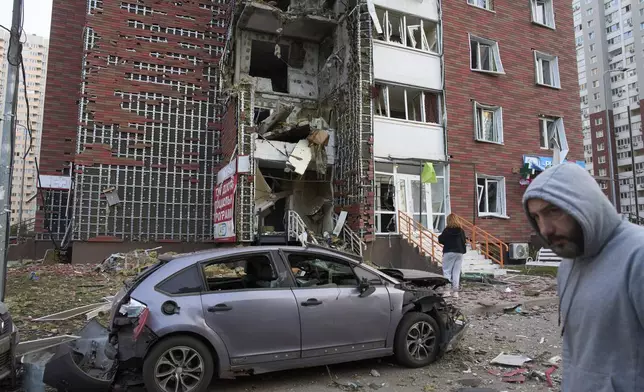 Residents react near their damaged multi-storey building damaged in Russia's missile and drone attack in Kyiv, Ukraine, Tuesday, June 10, 2025. (AP Photo/Efrem Lukatsky)