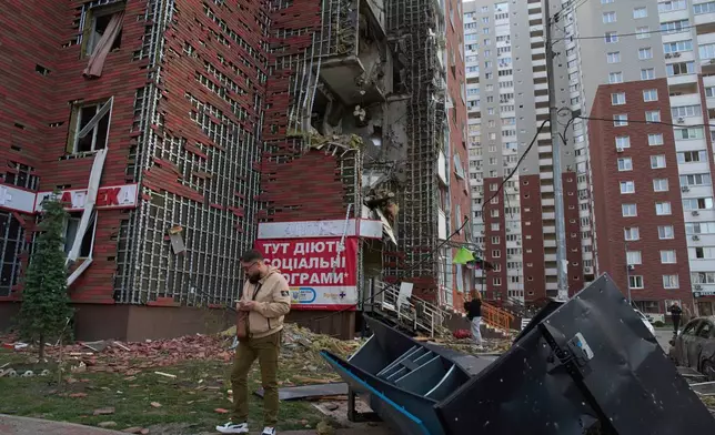 Residents react near their damaged multi-storey building damaged in Russia's massive missile and drone attack in Kyiv, Ukraine, Tuesday, June 10, 2025. (AP Photo/Efrem Lukatsky)