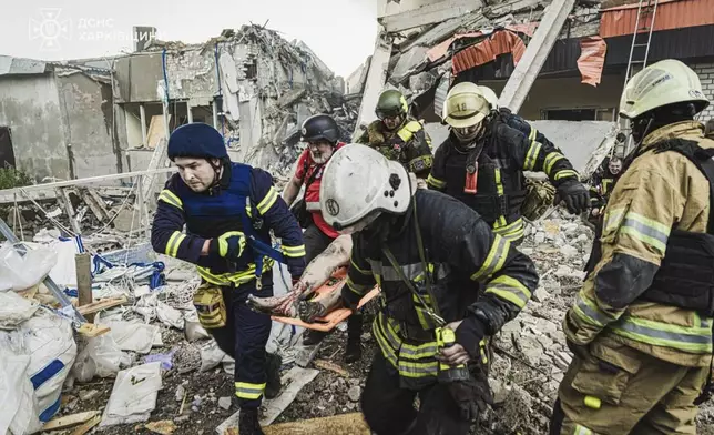 In this photo provided by the Ukrainian Emergency Service, emergency services personnel carry a body of a victim following a Russian rocket attack in Kharkiv, Ukraine, Tuesday, Tuesday, June 10, 2025. (Ukrainian Emergency Service via AP)
