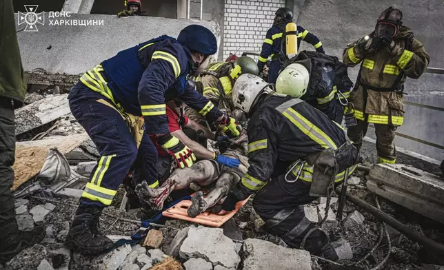 In this photo provided by the Ukrainian Emergency Service, emergency services personnel carry a body of a victim following a Russian rocket attack in Kharkiv, Ukraine, Tuesday, Tuesday, June 10, 2025. (Ukrainian Emergency Service via AP)