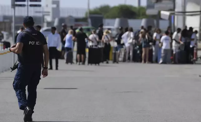 A Cypriot police officer patrols outside the departures terminal at Cyprus' main port in Limassol where they'll board the Israeli cruise ship Crown Iris to take them back to their homeland, on Thursday, June 19, 2025. (AP Photo/Petros Karadjias)