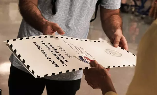 A voter receives his ballot at PS811, The Mickey Mantle School, in the mayoral primary election in New York, Tuesday, June 24, 2025. (AP Photo/Richard Drew)