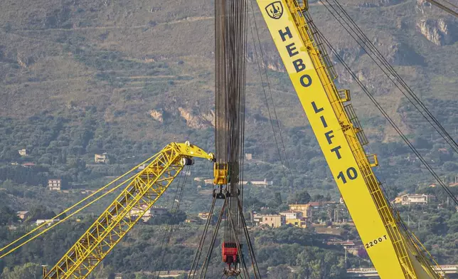 The hull of the superyacht Bayesian, which sank near Palermo, Sicily, on August 19, 2024, is lifted by cranes during salvage operations off the village of Porticello Saturday, June 21, 2025. (AP Photo/Salvatore Cavalli)