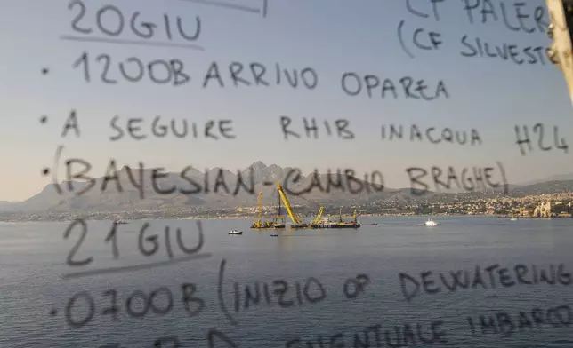 The salvage operations of the hull of the superyacht Bayesian, which sank near Palermo, Sicily, on August 19, 2024, are seen through the bridge of the Italian Coast Guard ship 'Diciotti' off the village of Porticello Saturday, June 21, 2025. (AP Photo/Salvatore Cavalli)