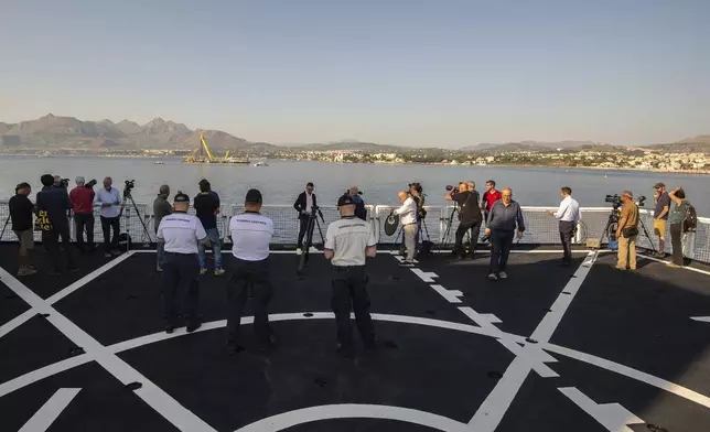 Memebers of the media on the Italian Coast Guard ship 'Dattilo' watch the hull of the superyacht Bayesian, which sank near Palermo, Sicily, on August 19, 2024, being pulled out of the sea and dewatered off the village of Porticello Saturday, June 21, 2025. (AP Photo/Salvatore Cavalli)
