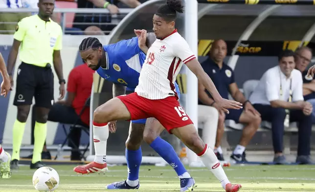 Canada's Nathan Saliba (19) pushes off Curacao's Jürgen Locadia, left, as he moves the ball during a CONCACAF Gold Cup soccer match Saturday, June 21, 2025, in Houston, Texas. (AP Photo/Michael Wyke)