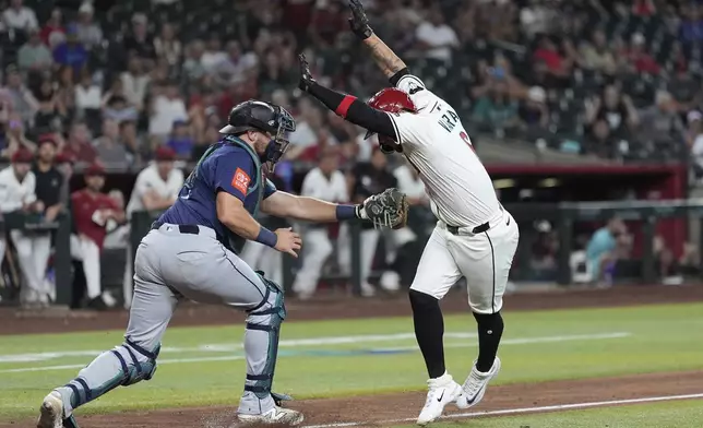 Arizona Diamondbacks' Ildemaro Vargas, right, avoids the tag by Seattle Mariners catcher Cal Raleigh, left, but is ruled out of the baseline for an out during the 10th inning of a baseball game Monday, June 9, 2025, in Phoenix. (AP Photo/Ross D. Franklin)