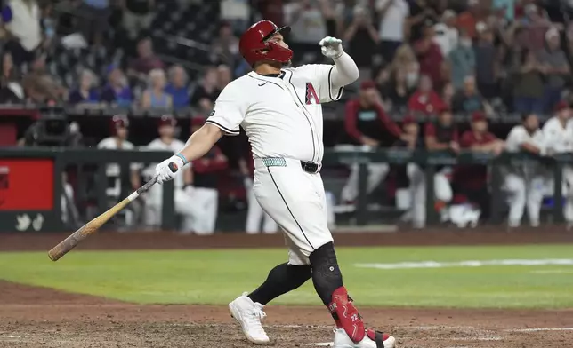 Arizona Diamondbacks' Josh Naylor watches the flight of his walk off grand slam to beat the Seattle Mariners during the 11th inning of a baseball game Monday, June 9, 2025, in Phoenix. (AP Photo/Ross D. Franklin)