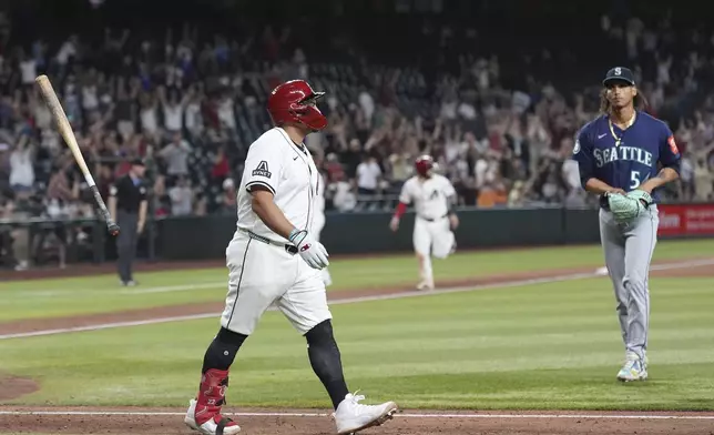 Arizona Diamondbacks' Josh Naylor, left, flips his bat as he watches the flight of his walk off grand slam against Seattle Mariners pitcher Carlos Vargas, right, during the 11th inning of a baseball game Monday, June 9, 2025, in Phoenix. (AP Photo/Ross D. Franklin)