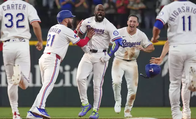 Texas Rangers' Adolis García, center, celebrates with Jake Burger (21), Wyatt Langford, center right, and other teammates after hitting a single that scored Evan Carter (32) during the 11th inning of a baseball game against the Chicago White Sox, Saturday, June 14, 2025, in Arlington, Texas. (AP Photo/LM Otero)