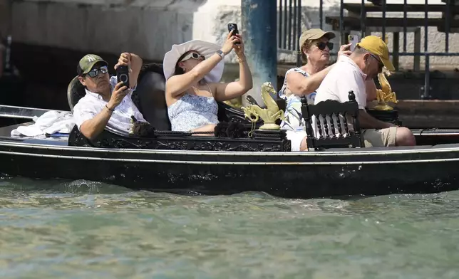A gondola carries tourists in front of the Aman Hotel along the Grand Canal in Venice, Italy, on Thursday, June 26, 2025, ahead of festivities in the lagoon city reportedly linked to a wedding celebration for Jeff Bezos and Lauren Sánchez. (AP Photo/Luca Bruno)