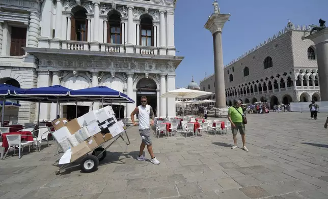 A man hauls a cart of supplies through Venice, Italy, on Wednesday, June 25, 2025, ahead of festivities in the lagoon city reportedly linked to a wedding celebration for Jeff Bezos and Lauren Sánchez. (AP Photo/Luca Bruno)
