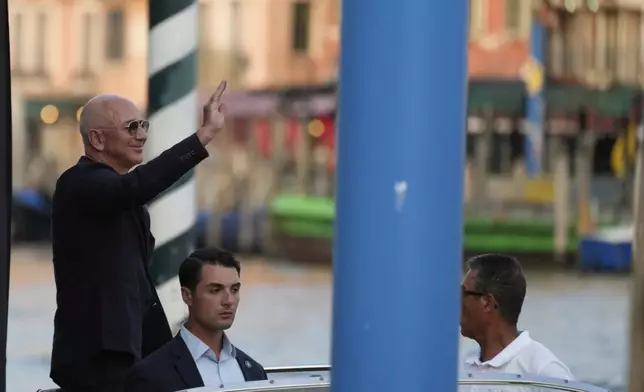 Amazon multi-billionaire founder Jeff Bezos waves as he leaves by boat an hotel in Venice, Italy, on Wednesday, June 25, 2025, ahead of festivities in the lagoon city reportedly linked to his wedding with Lauren Sanchez. (AP Photo/Luca Bruno)