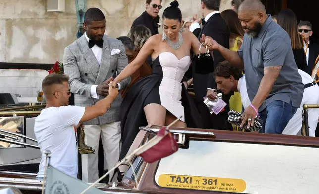 Usher, left, and his wife Jennifer Goicoechea leave a hotel ahead of the anticipated wedding celebrations of Jeff Bezos and Lauren Sanchez, in Venice, Italy, Friday, June 27, 2025. (AP Photo/Luigi Costantini)