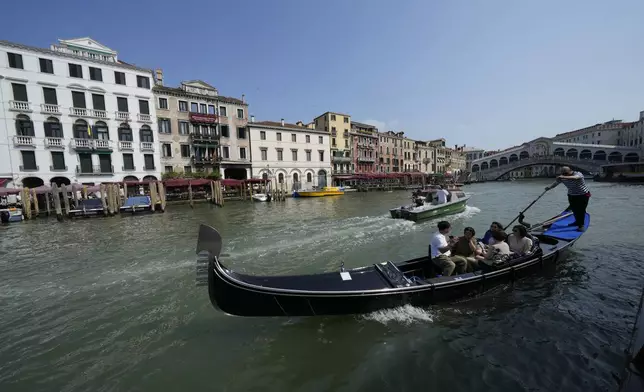 A gondolier tours tourists along the Grand Canal in Venice, Italy, on Wednesday, June 25, 2025, ahead of festivities in the lagoon city reportedly linked to a wedding celebration for Jeff Bezos and Lauren Sánchez. (AP Photo/Luca Bruno)