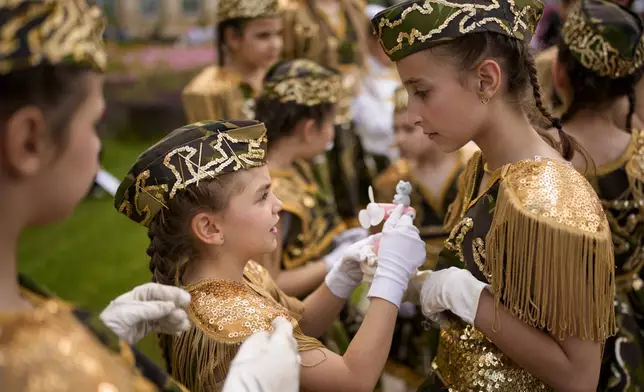 Students of a dance school check their outfits outside Romania's Palace of Parliament during a series of events marking International Children's Day in Bucharest, Romania, Sunday, June 1, 2025. (AP Photo/Andreea Alexandru)