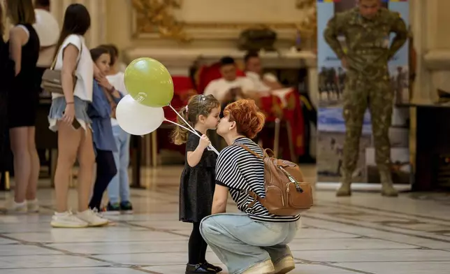 A girl gets a kiss inside Romania's Palace of Parliament during a series of events marking International Children's Day in Bucharest, Romania, Sunday, June 1, 2025. (AP Photo/Andreea Alexandru)