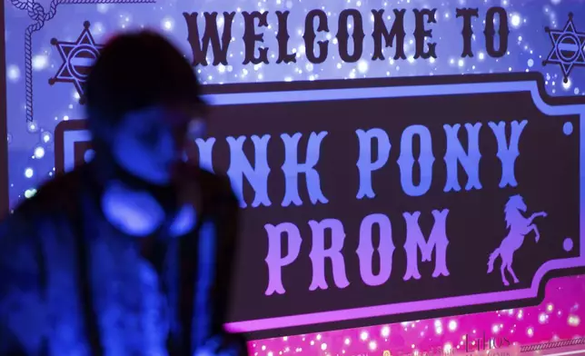 A DJ is seen in front of a sign for a "Pink Pony Prom" organized by the Sexual &amp; Gender Minority Youth Resource Center, part of New Avenues for Youth, a nonprofit dedicated to ending youth homelessness, on Friday, May 30, 2025, in Portland, Ore. (AP Photo/Jenny Kane)