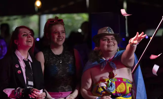 From left, June Arney and Caspian Brooks watch as Ambrose throws faux money on stage as a drag king performs during a "Pink Pony Prom" held to celebrate teen and young adult members of the LGBTQ+ community on Friday, May 30, 2025, in Portland, Ore. (AP Photo/Jenny Kane)