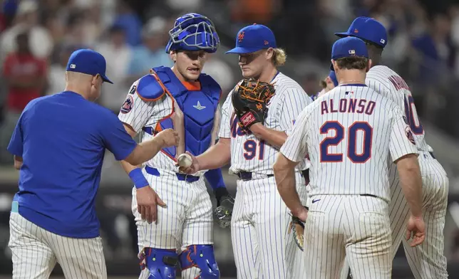 New York Mets pitcher Jonathan Pintaro, center, hands the ball to manager Carlos Mendoza as he leaves during the ninth inning of a baseball game against the Atlanta Braves Wednesday, June 25, 2025, in New York. (AP Photo/Frank Franklin II)