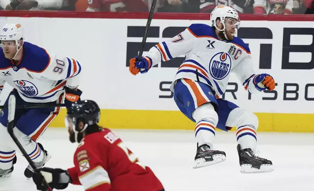 Edmonton Oilers' Connor McDavid (97) falls after a check from Florida Panthers' Aaron Ekblad (5) during the second period in Game 3 of the NHL hockey Stanley Cup finals in Sunrise, Fla., Monday, June 9, 2025. (Nathan Denette/The Canadian Press via AP)