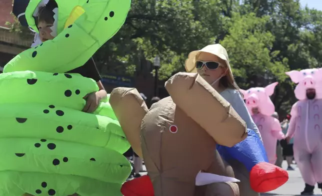 Children in inflatable costumes participate in the 'Rhino Rumble Road Race' to celebrate the 30th anniversary of the film 'Jumanji' in downtown Keene, N.H. on Saturday, June 21, 2025. (AP Photo/Leah Willingham)