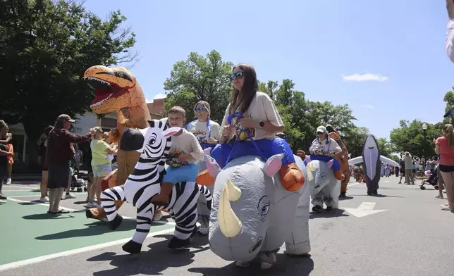 Crowds dressed in inflatable costumes participate in the 'Rhino Rumble Road Race' to celebrate the 30th anniversary of the film 'Jumanji' in downtown Keene, N.H. on Saturday, June 21, 2025. (AP Photo/Leah Willingham)