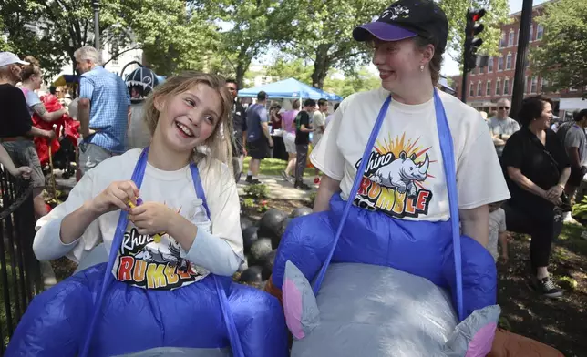 Juniper Thurston, right, and 9-year-old daughter Madison Christgau celebrate the 30th anniversary of the film 'Jumanji' by wearing inflatable rhino costumes in downtown Keene, N.H. on Saturday, June 21, 2025. (AP Photo/Leah Willingham)