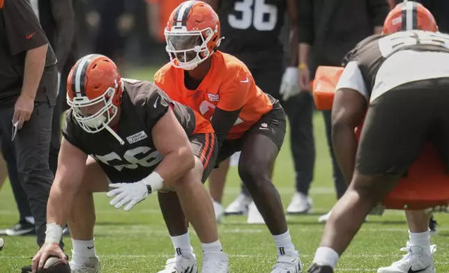 Cleveland Browns quarterback Shedeur Sanders, center, prepares to take the snap from center Luke Wypler (56) during practice at NFL football minicamp in Berea, Ohio, Tuesday, June 10, 2025. (AP Photo/Sue Ogrocki)