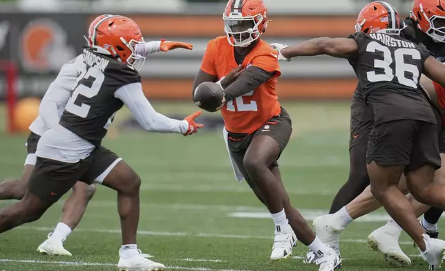Cleveland Browns quarterback Shedeur Sanders, center, hands off to running back Dylan Sampson, left, at NFL football minicamp in Berea, Ohio, Tuesday, June 10, 2025. (AP Photo/Sue Ogrocki)