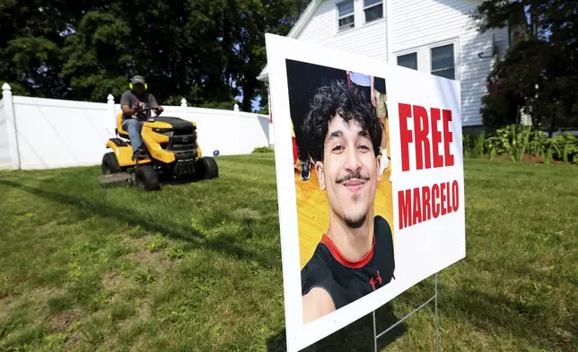 A homeowner around a sign supporting Marcelo Gomes Da Silva, who was arrested on his way to volleyball practice last weekend, on Thursday, June 5, 2025 in Milford, Mass. (AP Photo/Mark Stockwell)
