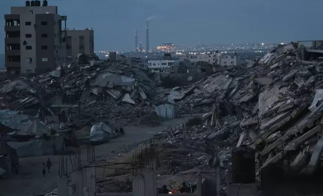 Palestinians displaced by the Israeli air and ground offensive on the Gaza Strip stand surrounded by destroyed buildings during the dusk in an area in Gaza City, Monday, June 2, 2025. (AP Photo/Jehad Alshrafi)