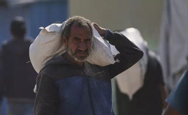 A Palestinian man carries a bag of food after receiving aid from the Gaza Humanitarian Foundation, a U.S.-backed organization approved by Israel, in Khan Younis, southern Gaza Strip, Sunday, June 1, 2025. (AP Photo/Abdel Kareem Hana)