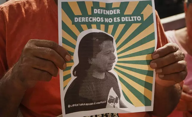 A man holds a poster of Alejandro Henriquez outside the courts during their hearing in Santa Tecla, El Salvador, Friday, May 30, 2025. The National Civil Police arrested them for protesting near the presidnetial residence. (AP Photo/Salvador Melendez)