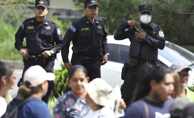 National Police stand behind the relatives of Alejandro Henriquez and Jose Angel Perez outside the courts during the men's hearing in Santa Tecla, El Salvador, Friday, May 30, 2025. The National Civil Police arrested them for protesting near the presidnetial residence. (AP Photo/Salvador Melendez)