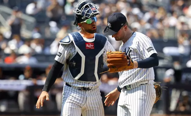 New York Yankees catcher J.C. Escarra and pitcher Clarke Schmidt chat during the seventh inning of a baseball game against the Baltimore Orioles, Saturday, June 21, 2025, in New York. (AP Photo/Noah K. Murray)