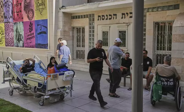 Patients rest outdoors after a building of the Soroka hospital complex was hit by a missile fired from Iran in Beersheba, Israel, Thursday, June 19, 2025. (AP Photo/Leo Correa)