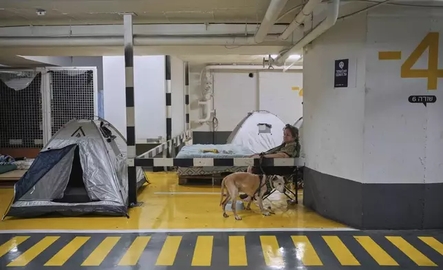 People take shelter in a parking garage as a precaution against possible Iran missile attacks, in Tel Aviv, Israel, Wednesday, June 18, 2025. (AP Photo/Ohad Zwigenberg)