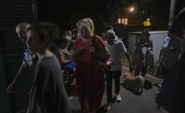 People arrive to take shelter during air raid sirens warning of incoming strikes by Iran, in Tel Aviv, Israel, early Thursday, June 19, 2025. (AP Photo/Ohad Zwigenberg)