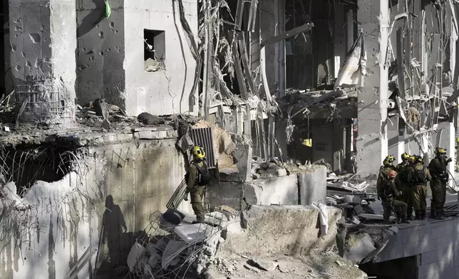 Rescue workers and military personnel inspect the site of a direct hit from an Iranian missile strike in Ramat Gan, Israel, Thursday, June 19, 2025. (AP Photo/Oded Balilty)