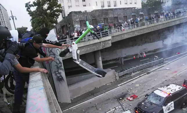A protester throws a scooter at a police vehical near the metropolitan detention center of downtown Los Angeles, Sunday, June 8, 2025, following last night's immigration raid protest. (AP Photo/Jae C. Hong)