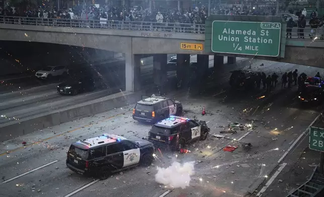 EDS NOTE: OBSCENITY A flash bomb explodes on the 101 Freeway near the metropolitan detention center of downtown Los Angeles, Sunday, June 8, 2025, following last night's immigration raid protest. (AP Photo/Eric Thayer)