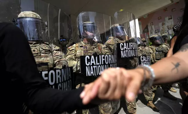 Protesters clasp hands in front of a line of California National Guard, Monday, June 9, 2025, at a Federal Building in downtown Los Angeles. (AP Photo Jae Hong)