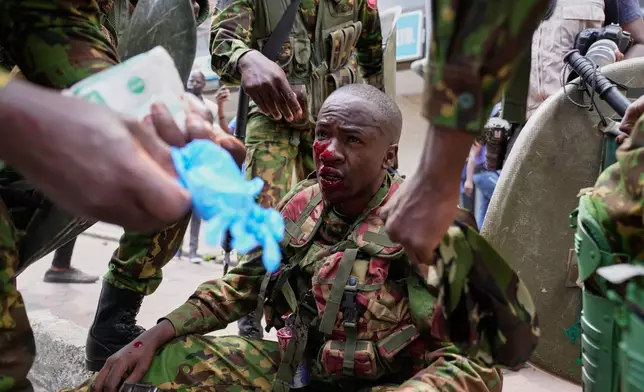 A police officer wounded during protests on the one-year anniversary of deadly anti-tax demonstrations is attended to in Nairobi, Kenya, Wednesday, June 25, 20125. (AP Photo/Brian Inganga).