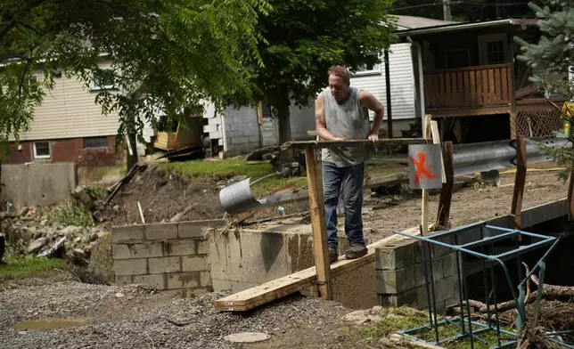 John Black puts up a board over a washed out foot bridge over Battle Run creek, Monday, June 16, 2025, in Valley Grove, W.Va. (AP Photo/Carolyn Kaster)