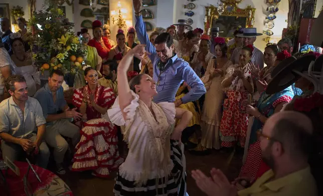 Pilgrims dance Sevillanas in a home in El Rocio village, near Aznalcazar, Spain, during the annual Catholic pilgrimage to the shrine of the Virgin of El Rocio that draws hundreds of thousands of faithful, Sunday, June 8, 2025. (AP Photo/Emilio Morenatti)
