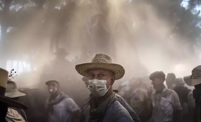 Pilgrims walk through dusty terrain near Aznalcazar, Spain, during the annual Catholic pilgrimage to the shrine of the Virgin of El Rocio, that draws hundreds of thousands of faithful, Friday, June 6, 2025. (AP Photo/Emilio Morenatti)